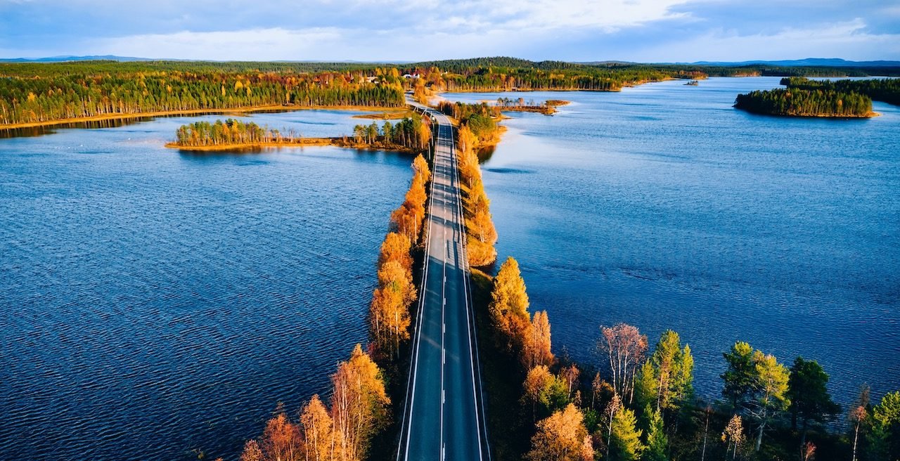 Aerial view of bridge across blue lakes in colorful autumn forest in Finland Lapland.